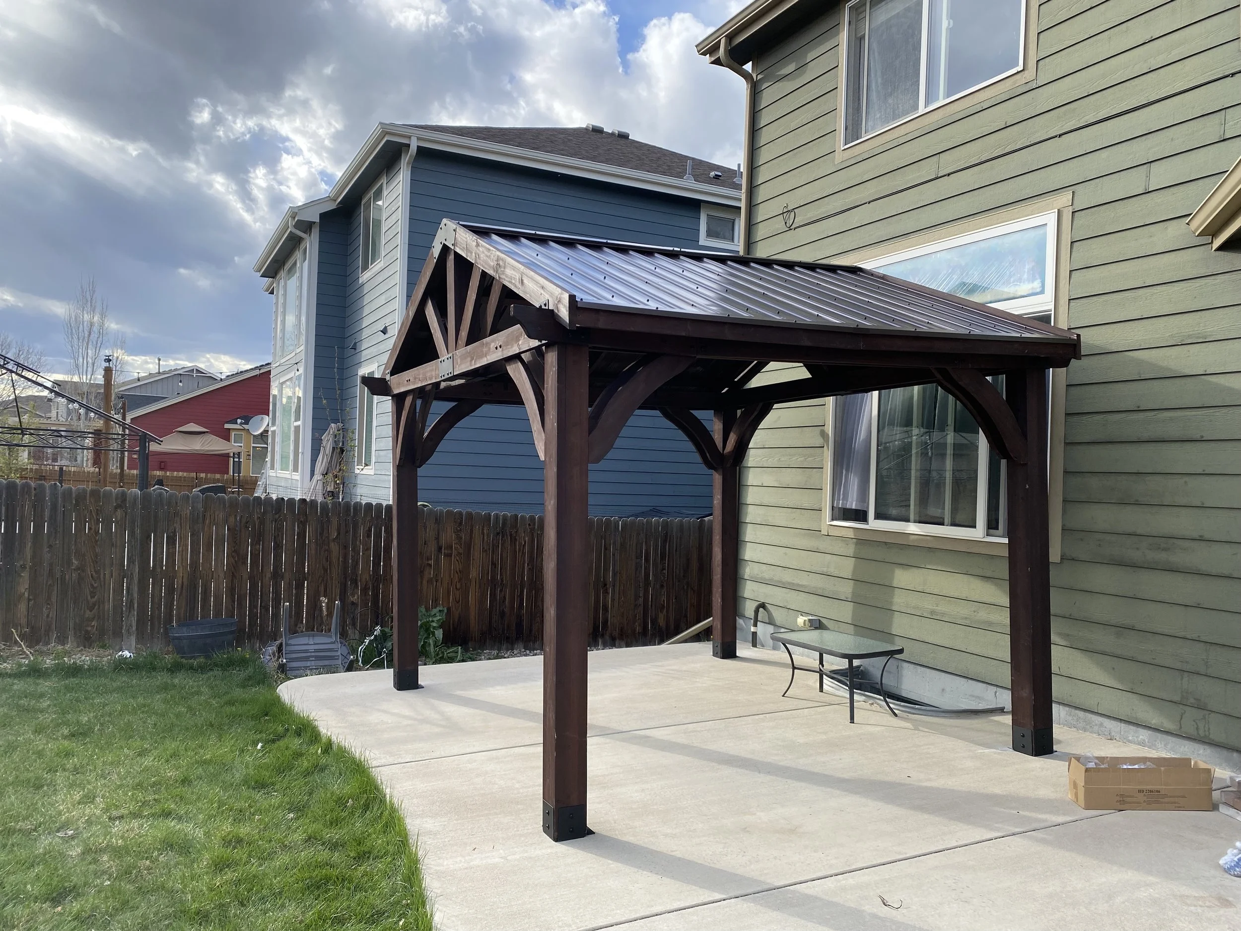 Timber pergola with a standing seam metal roof over a back patio