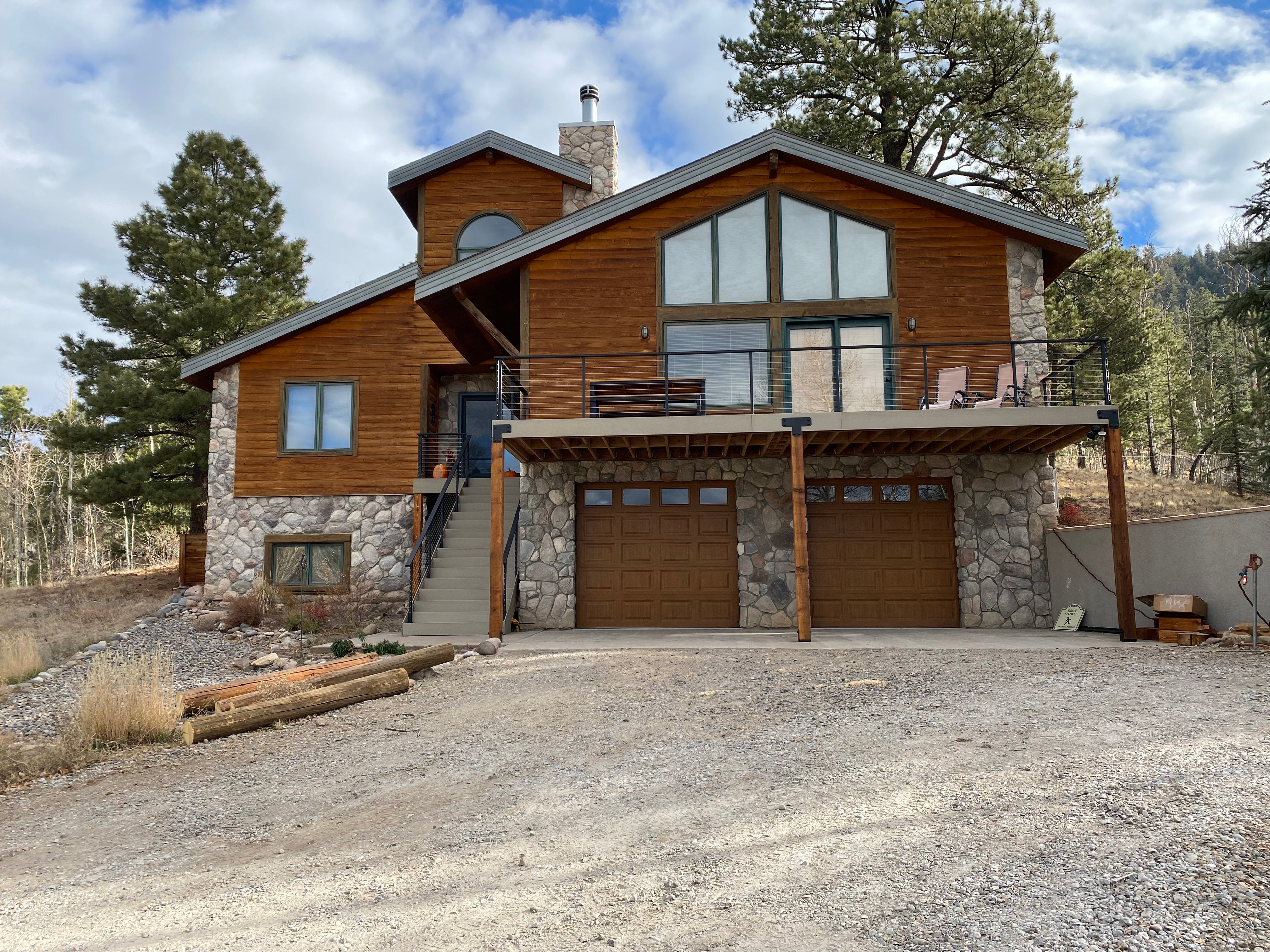 Log home exterior with rebuilt deck framing and stone veneer