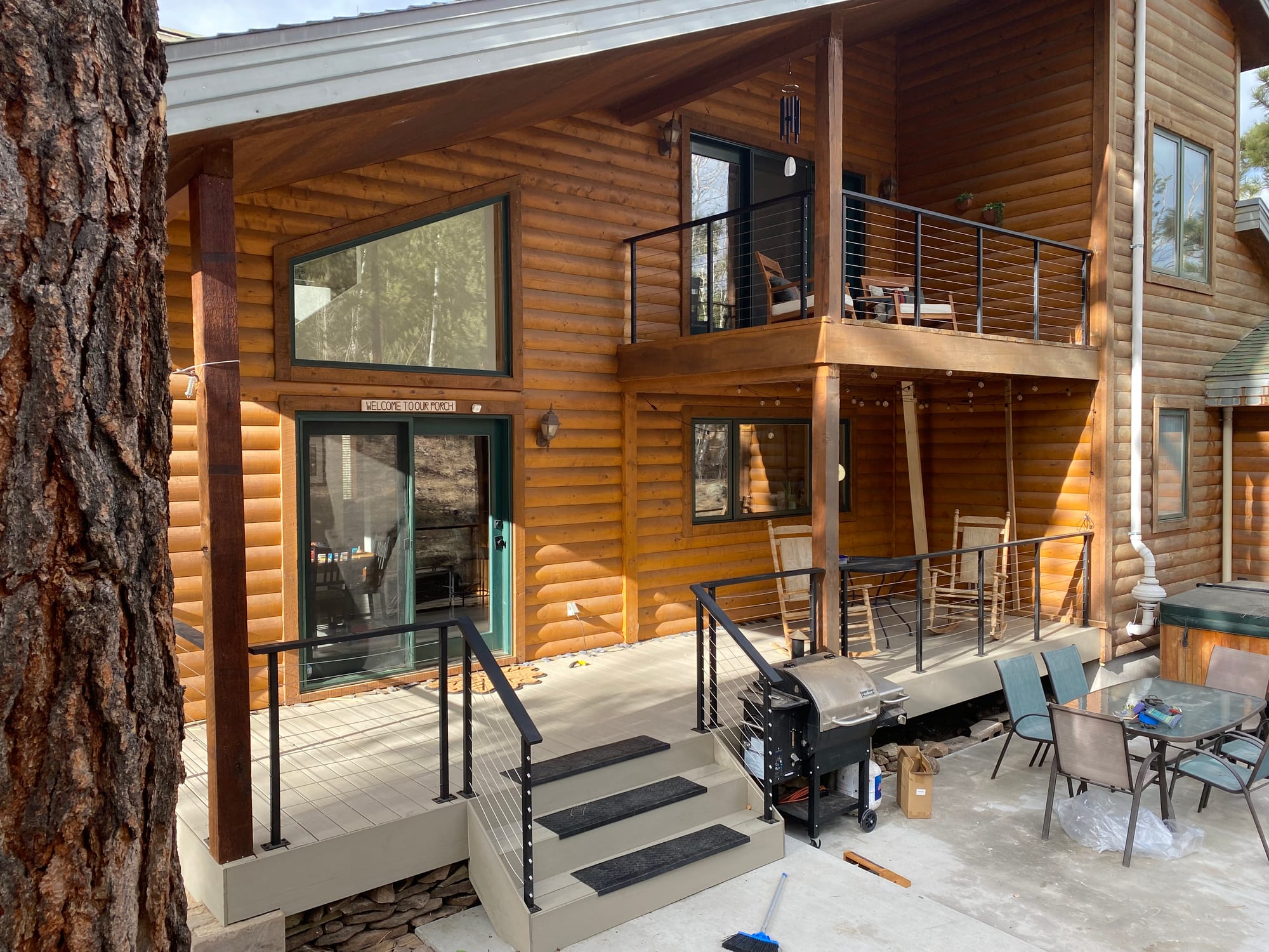 Two-story covered porch on a log home with timber posts and cable railing