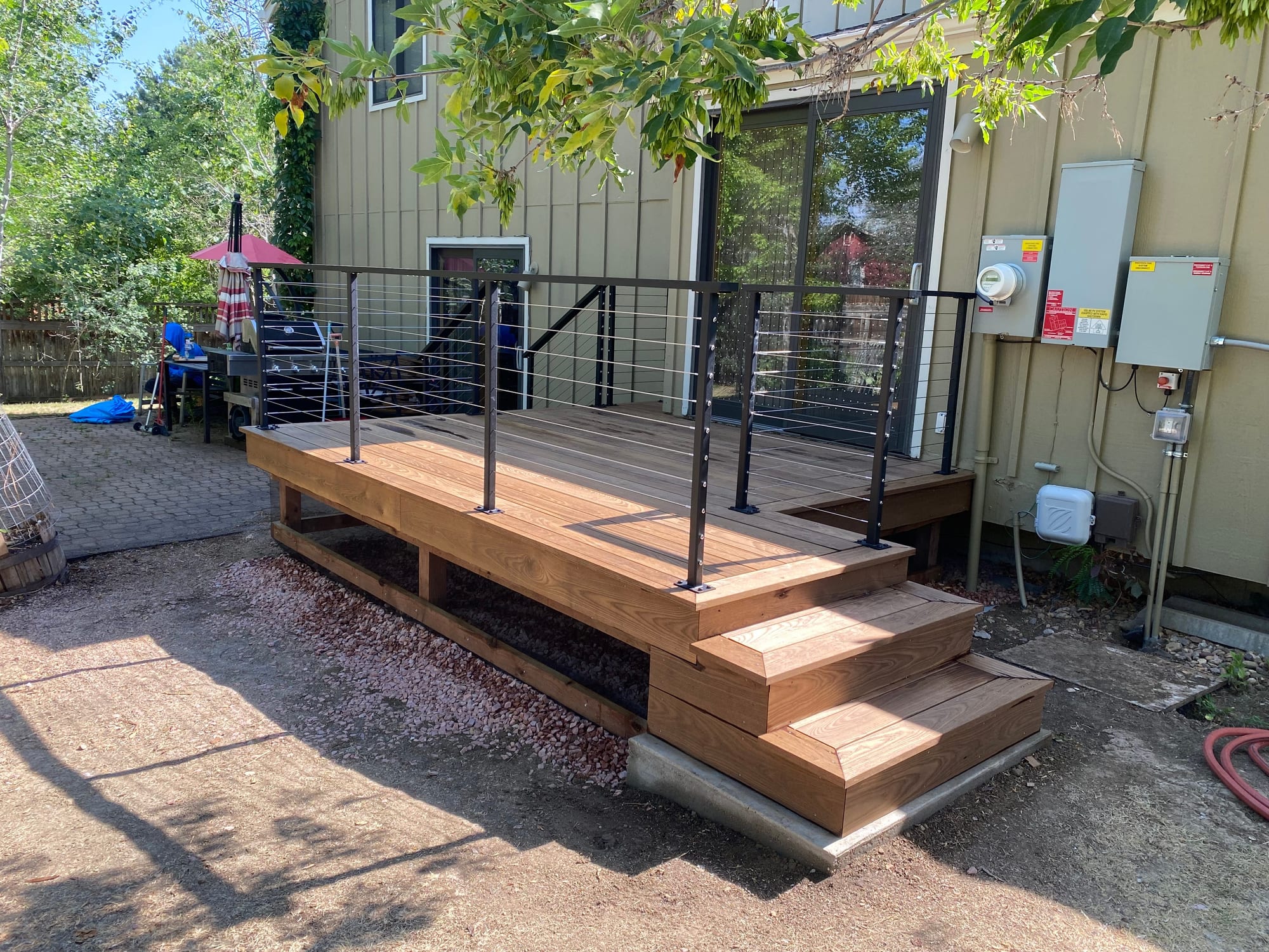 New cedar deck with black posts and horizontal cable railing behind a Boulder home